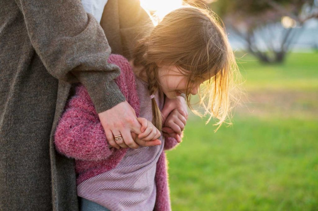 A comforting scene of a parent holding a small child in their arms in a park, representing care and parental support in custody cases managed by Judith Ramos, Attorney at Law in Miami, Florida.