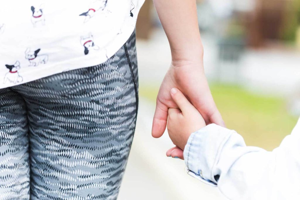 Close-up view of a young child holding an adult’s hand, representing security and parental support in child support cases managed by Judith Ramos, Attorney at Law in Miami, Florida.