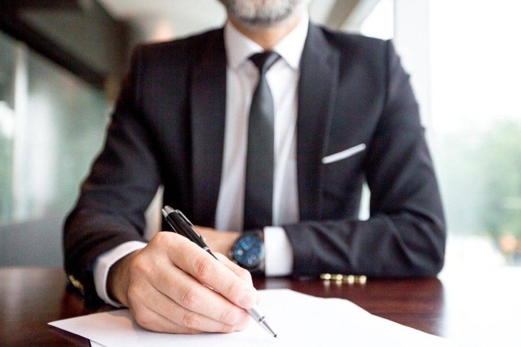 A professional discreetly signing legal documents, face not visible, representing Judith Ramos, Attorney at Law’s commitment to confidentiality in managing complex divorce cases in Miami, Florida.
